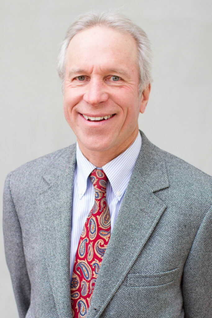 David Rasmussen smiles wearing a suit and tie